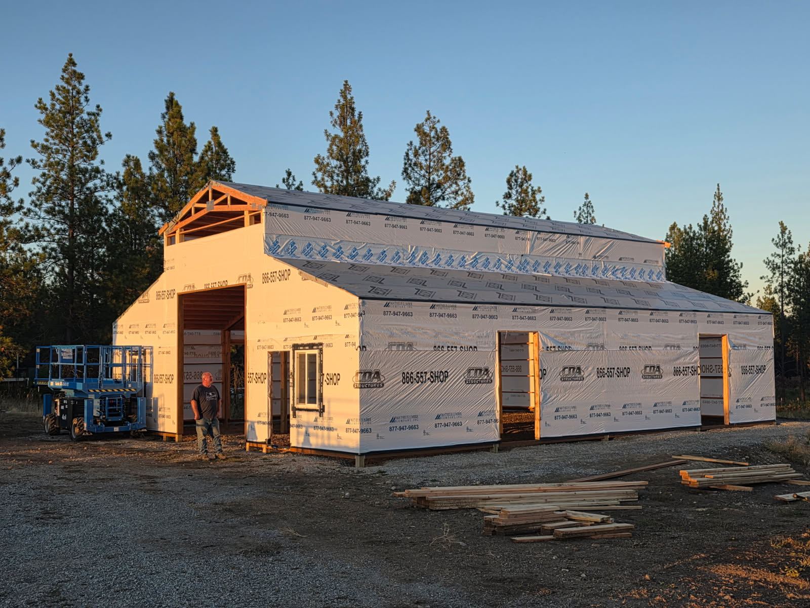 The barn sheathed and covered in building wrap printed with the CDA Structures logo, openings still open