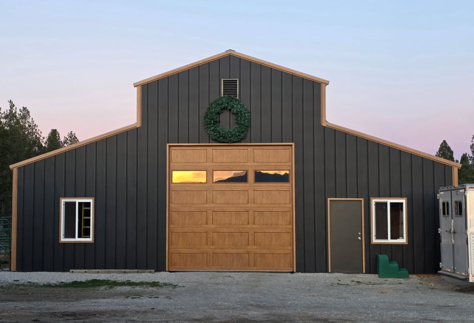 The finished monitor barn at dusk, with the overhead door, walk door and windows installed